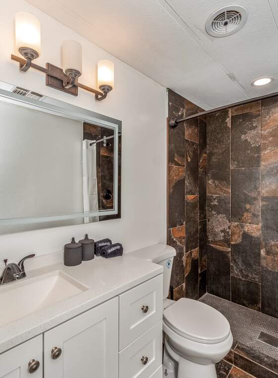 A bathroom with a stone-tiled shower and polished vanity